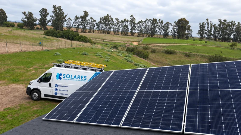 Paneles solares en primer plano y vehículo de K Solares en un terreno verde.