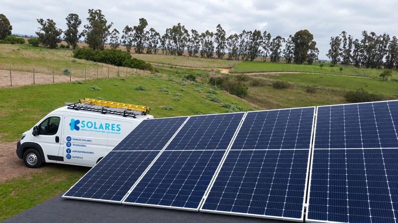 Conjunto de paneles solares y vehículo de K Solares en un paisaje de campo.